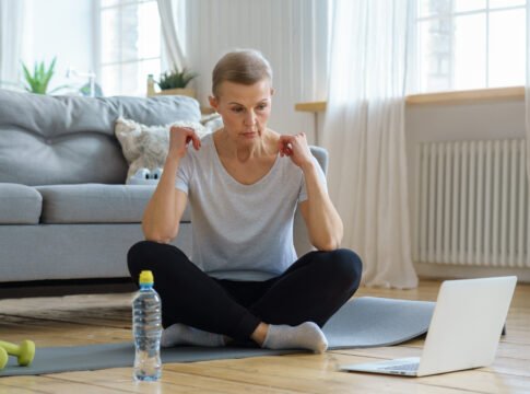 Senior woman online training in living room. Mature female exercising with laptop watching fitness Keto Crashes Your Electrolyte Balance
